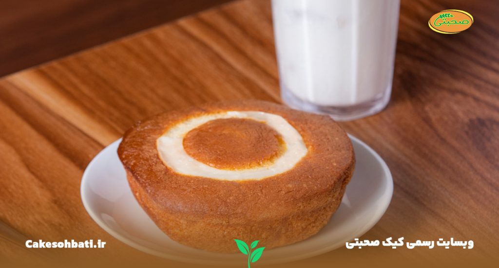 تصویری از کیک کرمدار صحبتی که یک میان وعده برای کودکان است، بر روی یک ظرف و قرار داده شده بر روی میز چوبی که در کنار آن یک لیوان شیر دیده میشود.