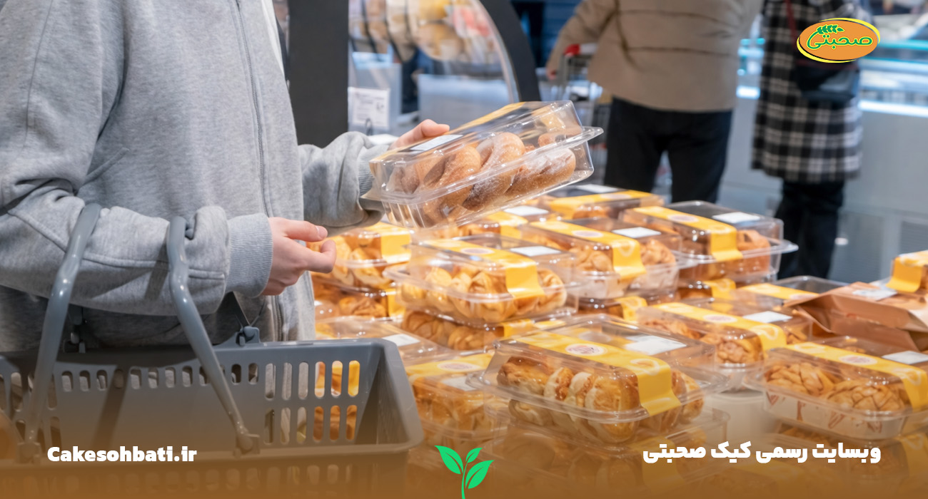نمایی از یک فروشگاه و تعداد زیادی کیک بسته‌بندی شده و مردم که درحال خرید کیک عمده هستند.